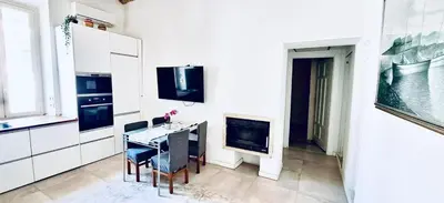 a white kitchen with a table and a fireplace at Cozy Flat near the Vatican! in Rome