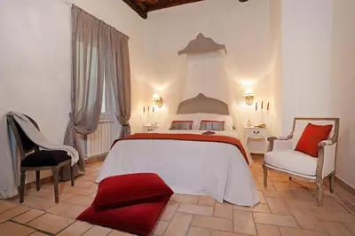 a bedroom with a large bed and two chairs at Madonna de' Monti Suites in Rome
