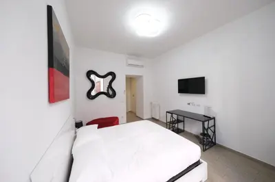 a white bedroom with a white bed and a television at Roman Forum Holiday Termini in Rome