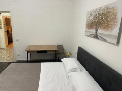 a bedroom with a bed and a table with a tree on the wall at LarisaSuite in Rome