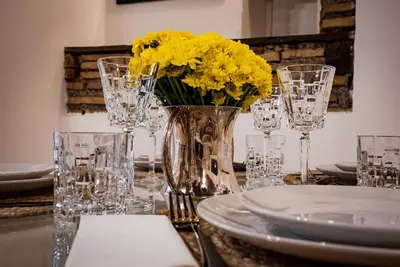 a table with glasses and a vase of yellow flowers at Pantheon Appartamento Costaguti in Rome