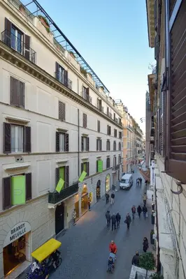 a group of people walking down a street next to a building at Gravina Suite Frattina in Rome