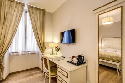 a room with a desk and a bed and a mirror at Gravina Suite Frattina in Rome