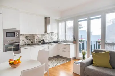a kitchen with white cabinets and a table and a couch at Casetta Pandosia - San Giovanni - Colosseo in Rome