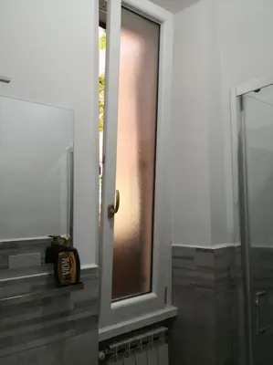 a door to a bathroom with a window and a clock at Notti di San Lorenzo in Rome