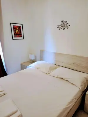 a bedroom with a white bed with a wooden headboard at Notti di San Lorenzo in Rome