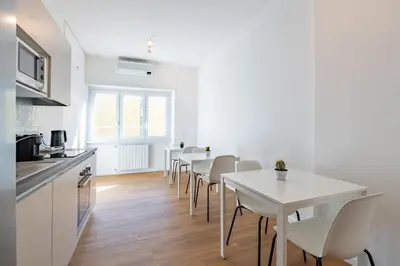 a kitchen and dining room with white tables and chairs at Relais Garbatella in Rome