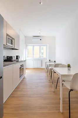 a kitchen and dining room with white counters and tables at Relais Garbatella in Rome