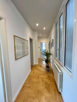 a hallway with white walls and wood floors and a potted plant at Sunrise House - San Giovanni in Rome