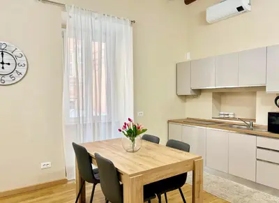 a kitchen with a wooden table with chairs and a clock at DaliTourism - Nazionale Charme in Rome