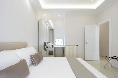 a white bedroom with a large bed and a white ceiling at Caruso Regal House in Rome