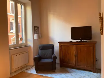 a living room with a chair and a television at Appartamento storico borgo Pio in Rome