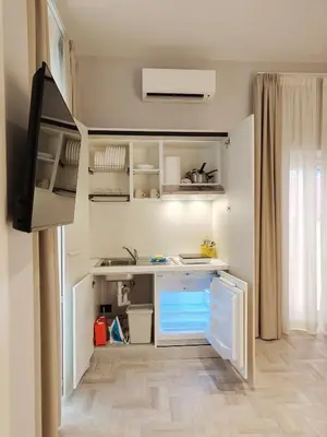 a small kitchen with white cabinets and a television at Crystal Domus in Rome