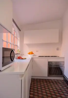 a white kitchen with a microwave and a sink at Deco Garden Apartment Trastevere in Rome