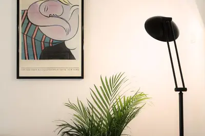 a black floor lamp next to a plant and a picture at Deco Garden Apartment Trastevere in Rome