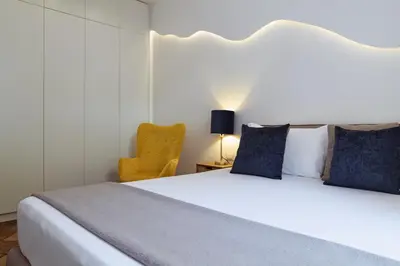 a bedroom with a large white bed and a yellow chair at Domus Duca Claudius I Classy Vatican Apartment With Private Garden in Rome