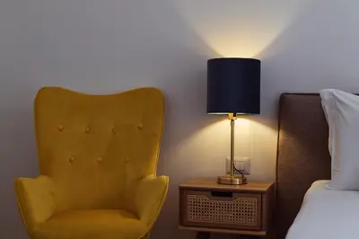 a yellow chair sitting next to a bed next to a lamp at Domus Duca Claudius I Classy Vatican Apartment With Private Garden in Rome