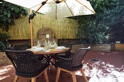 a table with chairs and an umbrella on a patio at Domus Duca Claudius I Classy Vatican Apartment With Private Garden in Rome