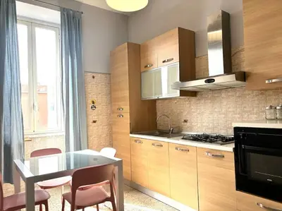 a kitchen with wooden cabinets and a table with chairs at Scalo Home in Rome