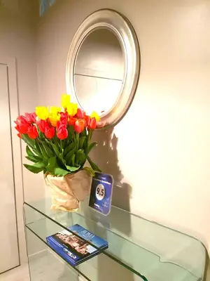 a glass table with a vase of flowers and a mirror at Living Rhome-SpanishSteps in Rome