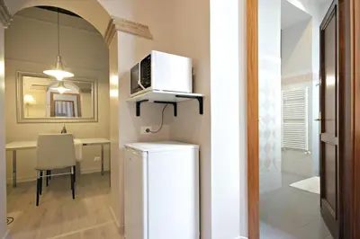 a kitchen and dining room with a microwave on top of a refrigerator at Living Rhome-SpanishSteps in Rome
