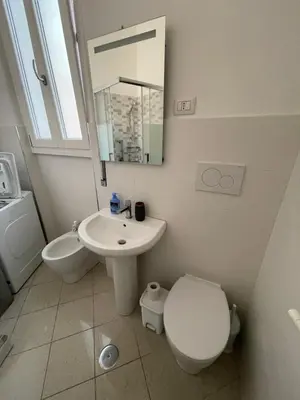 a white bathroom with a toilet and a sink at Anna's House in Rome