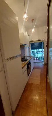 a kitchen with a white refrigerator and a wooden floor at Alloggio Turistico Agiati in Rome