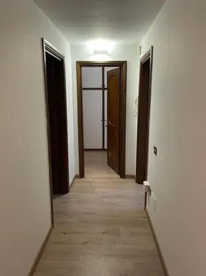 an empty hallway with three doors and a wooden floor at testaccio sei in Rome