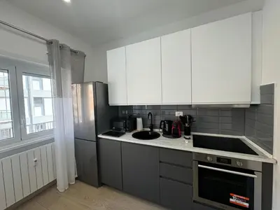 a kitchen with white cabinets and a stainless steel refrigerator at Chic&Elegant Retreat in Rome in Rome