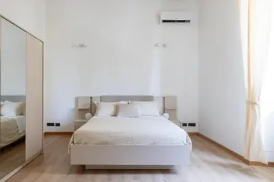 a white bedroom with a white bed and a mirror at Elegant Ostiense Suite in Rome