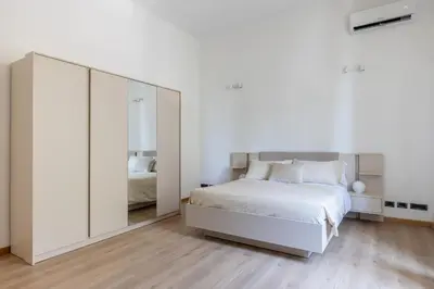 a bedroom with a large white bed and a mirror at Elegant Ostiense Suite in Rome