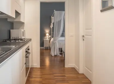 a kitchen with white cabinets and a wooden floor at Vatican Angels Casa Vacanze in Rome