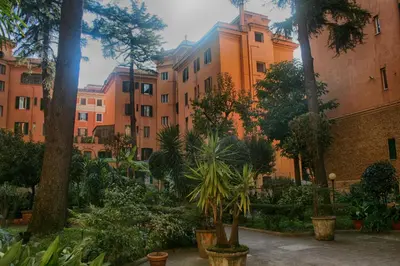 a courtyard with trees and plants in front of buildings at Vatican Angels Casa Vacanze in Rome