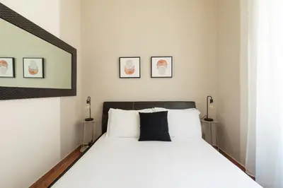 a bedroom with a large white bed with two lamps at Centro - casa a Trastevere in Rome