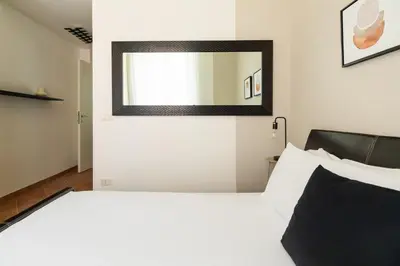 a bedroom with a white bed with a mirror on the wall at Centro - casa a Trastevere in Rome