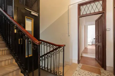 a hallway with a staircase with a black railing and a door at Centro - casa a Trastevere in Rome