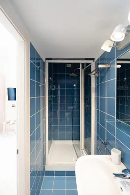 a blue tiled bathroom with a shower and a sink at Barletta Vatican Rooms in Rome