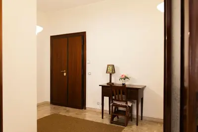 a hallway with a wooden door and a desk with a chair at Appartamento Scena Vaticana in Rome