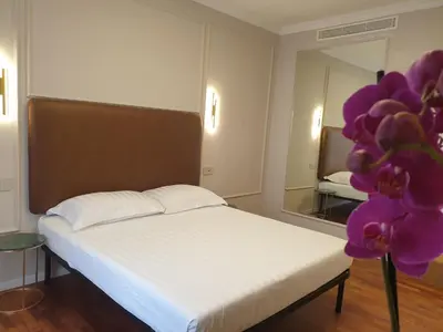 a bedroom with a bed and a mirror and purple flowers at Appian Private Suites in Rome