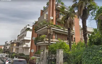 a tall building with palm trees in front of it at L'Attico di San Saba in Rome