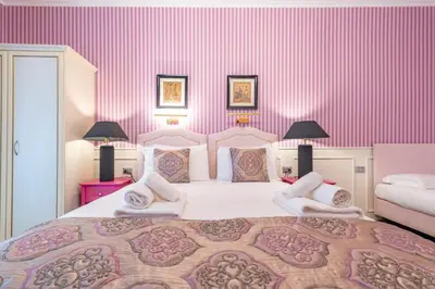 a bedroom with a large bed with pink walls at Catone Vatican Suites by Ghor in Rome