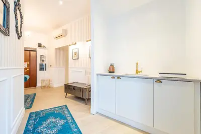 a kitchen with white cabinets and a blue rug at Catone Vatican Suites by Ghor in Rome