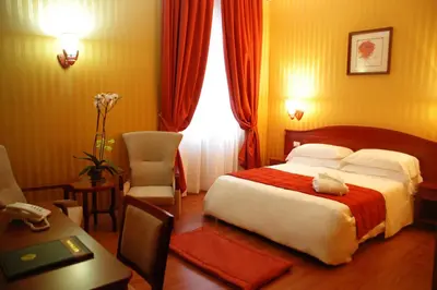 a hotel room with a large bed and a desk at Augusta Lucilla Palace in Rome