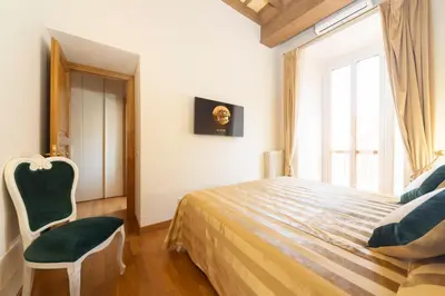 a bedroom with a bed and a chair and a window at Pantheon Suites in Rome in Rome