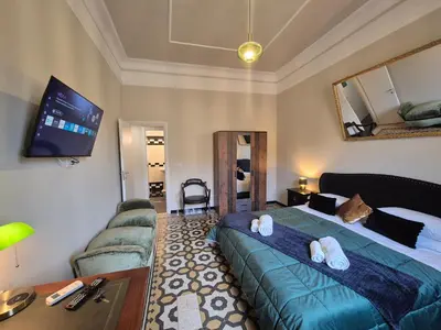 a bedroom with a bed and a couch and a tv at HEBE Eternity Rooms in Rome