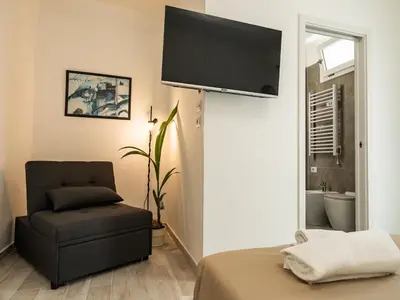 a living room with a chair and a flat screen tv at Felix Rooms in Rome