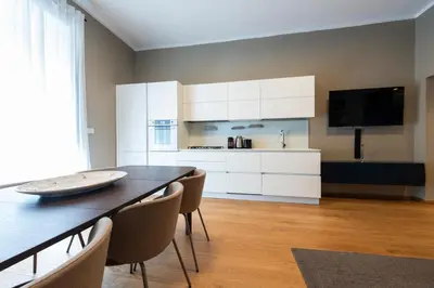 a kitchen with white cabinets and a table and chairs at Vatican Scipioni Apartment in Rome