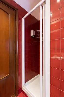 a red tiled shower with a mirror in a bathroom at Suite Bormida - Coppedè in Rome