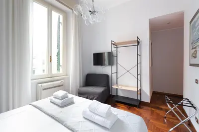a white bedroom with a bed and a chair at Suite Bormida - Coppedè in Rome