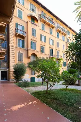 a large yellow building with trees in front of it at Suite Bormida - Coppedè in Rome